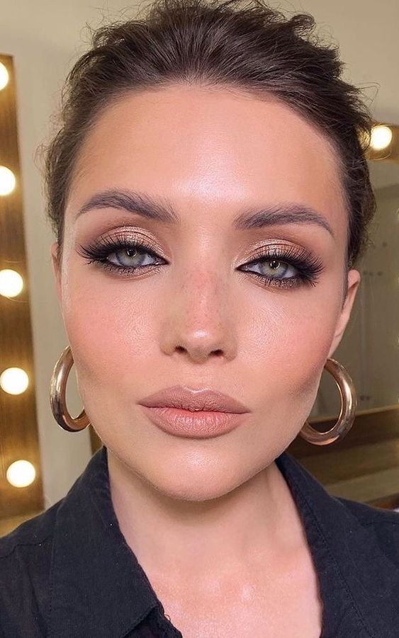 a special occasion makeup with rose gold eyeshadow, accented eyes with faux eyelashes, a nude lip and a touch of blush and highlighter