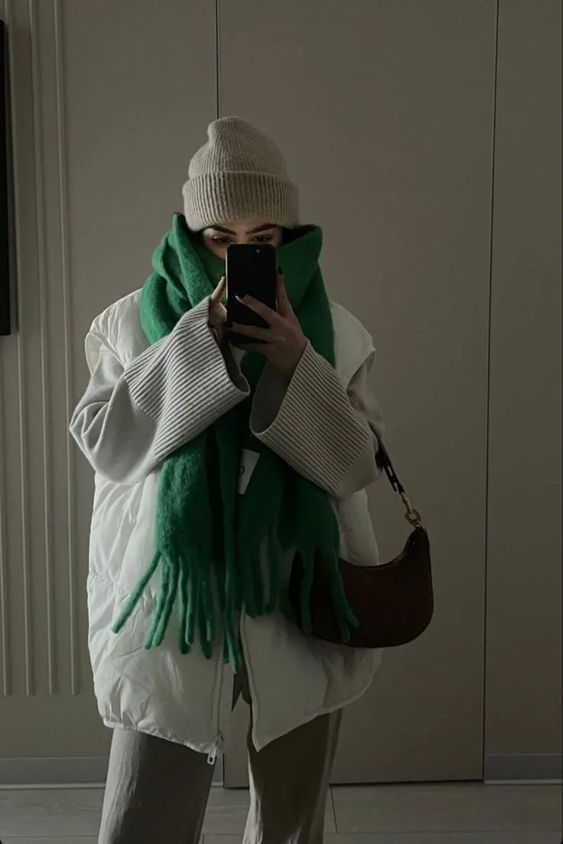 a stylish cold weather outfit with grey jeans, a dove grey sweater, a white quilted waistcoat, a grey beanie and a black bag plus a green scarf