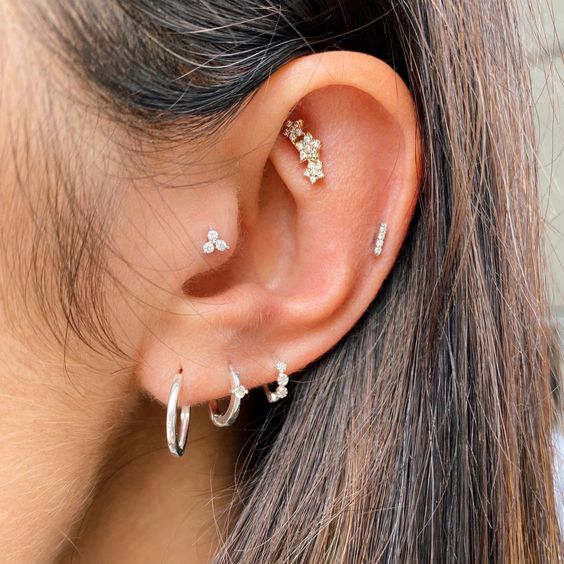 a super stylish and bold ear look with a tragus, faux rook, mid helix, triple lobe piercings, with white gold hoops and studs