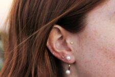 a tragus, double lobe, mid helix piercing done with gold hoops and a gold pearl earring are an amazing and chic combo