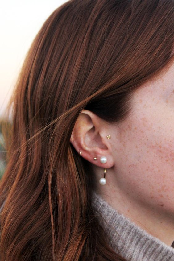 a tragus, double lobe, mid helix piercing done with gold hoops and a gold pearl earring are an amazing and chic combo