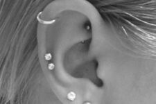 a triple lobe, double mid helix, helix and rook piercings with rhinestone and pearl studs and a hoop earring