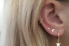 a triple lobe piercing done with gold studs and a hoop with a star, a mid helix piercing with a rhinestone hoop