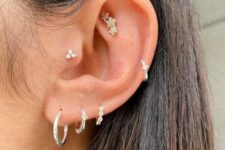 a triple lobe piercing with white gold hoops, a tragus, a faux rook and a mid helix done with hoops and studs