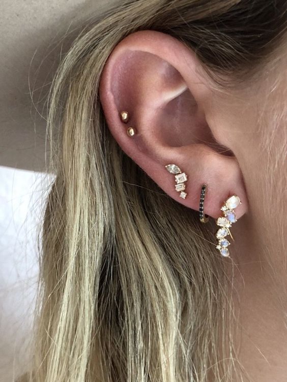 a triple lobe plus a double mid helix piercing done with bold rhinestone hoops and small gold studs