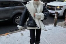 a white sweater, black skinnies tucked into knee boots, a black and white aviator coat and a black bag