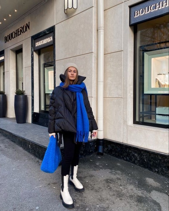 a winter outfit with a black puffer jacket, black skinnies tucked into white Chelsea boots, a bold blue scarf and a bag