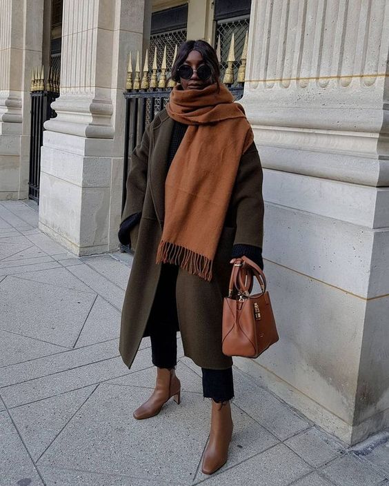 black jeans, brown boots, a dark grey midi coat, a beige scarf and an amber bag are a great combo for winter
