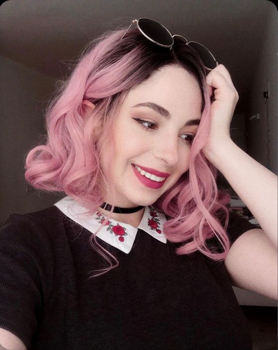 black roots and pastel pink hair in curls are a super bold and catchy combo to rock