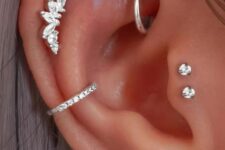bold and catchy ear styling with a double lobe, conch, helix, rook and double tragus piercing with bright studs and hoops