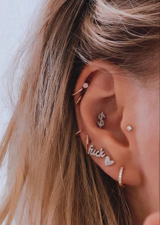 bold and fun ear styling with a multiple lobe, mid and upper helix, conch and tragus piercings done with studs, words and hoops