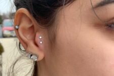 bold ear styling with a double lobe, a mid-helix and double tragus piercing done with rhinestone studs