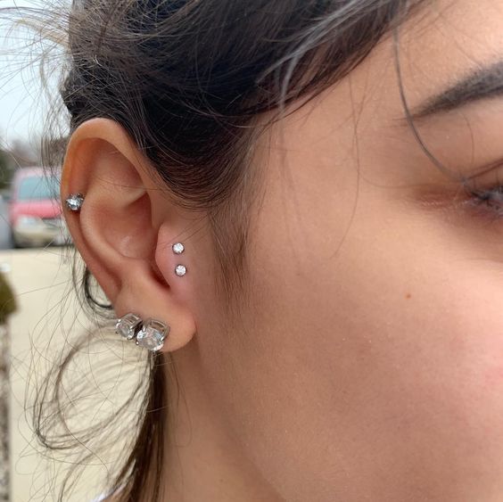 bold ear styling with a double lobe, a mid-helix and double tragus piercing done with rhinestone studs