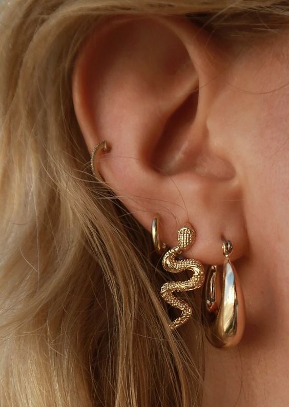 bold ear styling with a triple lobe and mid helix piercing, with bold gold earrings and a small and thin hoop