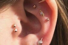 bright and catchy ear styling with a triple lobe, triple flat, double helix and double tragus piercing done with gold studs and hoops