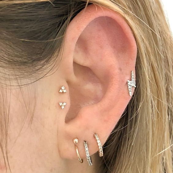 catchy ear styling with a double tragus, triple lobe and mid-helix piercing done with hoops and studs