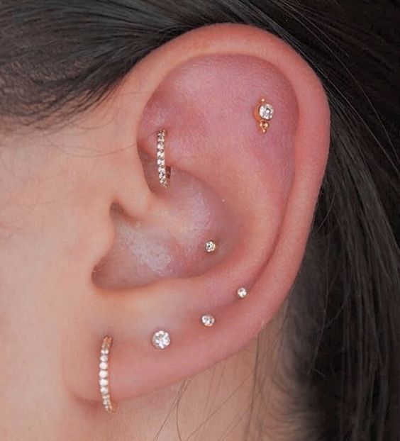 chic minimalist ear styling with a stacked lobe, conch, flat and rook piercings done with hoops and studs