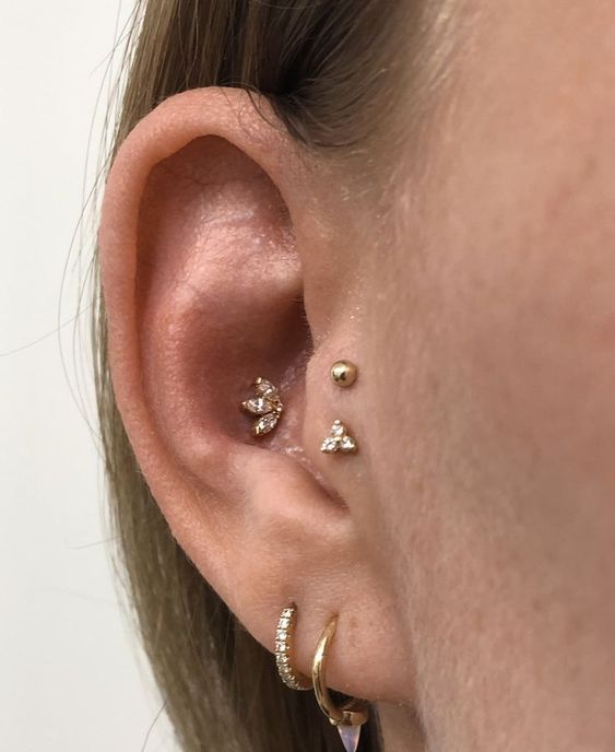 cool ear styling with a double lobe, a conch and double tragus piercing done with gold hoops and studs