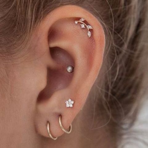delicate ear styling with stacked and high lobe, flat and conch piercings accented with hoops and studs