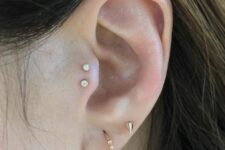 elegant and minimalist ear styling with a double tragus piercing and a double lobe one done with gold hoops and studs