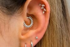 elegant ear styling with stacked lobe, high lobe, daith and flat piercings done with white gold hoops and studs looks wow