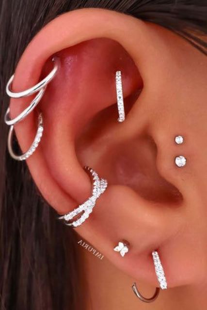 glam and chic ear styling with a double tragus, double lobe, conch, triple helix and a rook piercing done with studs and hoops