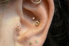 glam ear styling with stacked lobe piercings, a double conch piercing, a double tragus, a helix piercing all done with gold studs and hoops