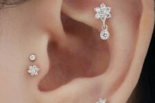 gorgeous ear accessorizing with daith, lap and double tragus piercing with shiny rhinestone floral studs