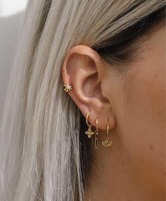 gorgeous ear styling with a triple lobe and a mid helix piercing done with gold hoop earrings with pendant and a star