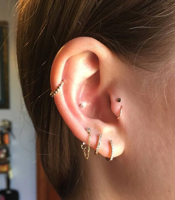 minimal ear styling with a triple lobe, conch, mid-helix, double tragus piercing done with hoops and studs is lovely