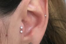minimalist ear styling with a double tragus, a lobe and a mid-helix piercing done with matching white rhinestone studs