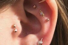 multiple ear piercings with a triple flat, a double helix, a double tragus and a triple lobe piercing done with gold studs and hoops