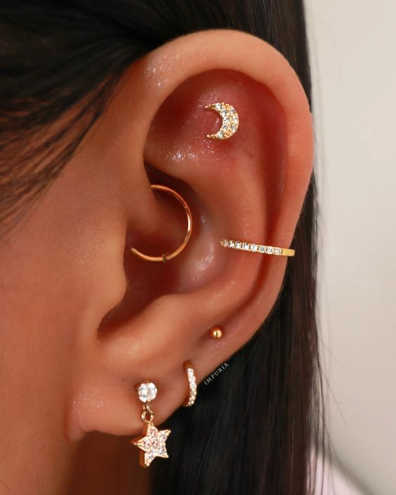 multiple ear piercings with stacked and high lobe, daith, conch and flat piercing, accented with gold hoops and studs