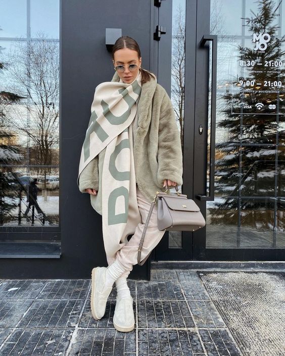 neutral sweatpants, creamy socks and loafers, a light green faux fur coat, a printed scarf and a grey bag for cold weather