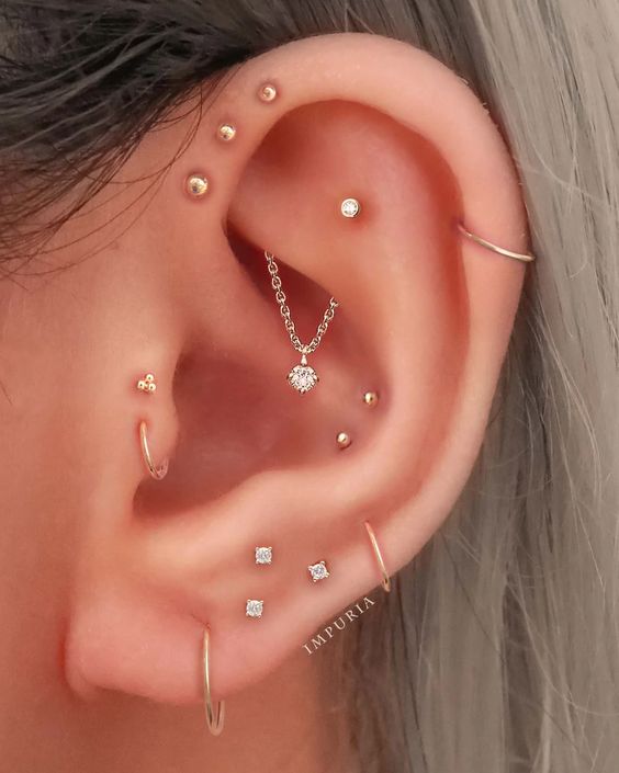 super bold ear styling with a double tragus, multiple lobe, double conch, triple forward helix, helix and flat piercings with studs and hoops