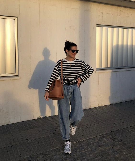 a Breton stripe top, blue baggy jeans, neutral trainers, a large brown bag and a black belt are a lovely look for every day