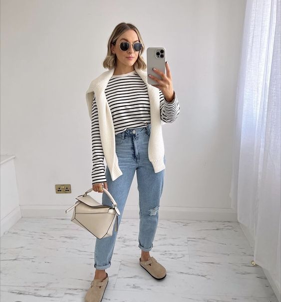 a Breton stripe top, blue cuffed jeans, nude flats, a white jumper over the shoulders, a neutral bag for spring