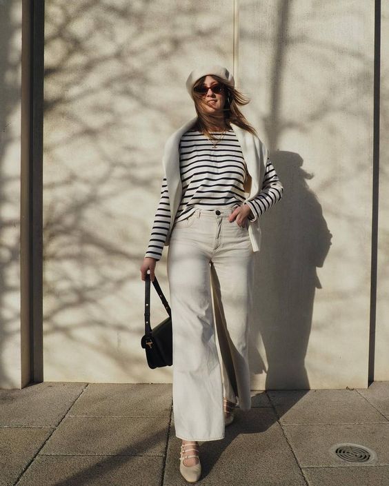 a Breton stripe top, white jeans, nude Mary Jane shoes, a white jumper over the shoulders, a white beret, a black bag