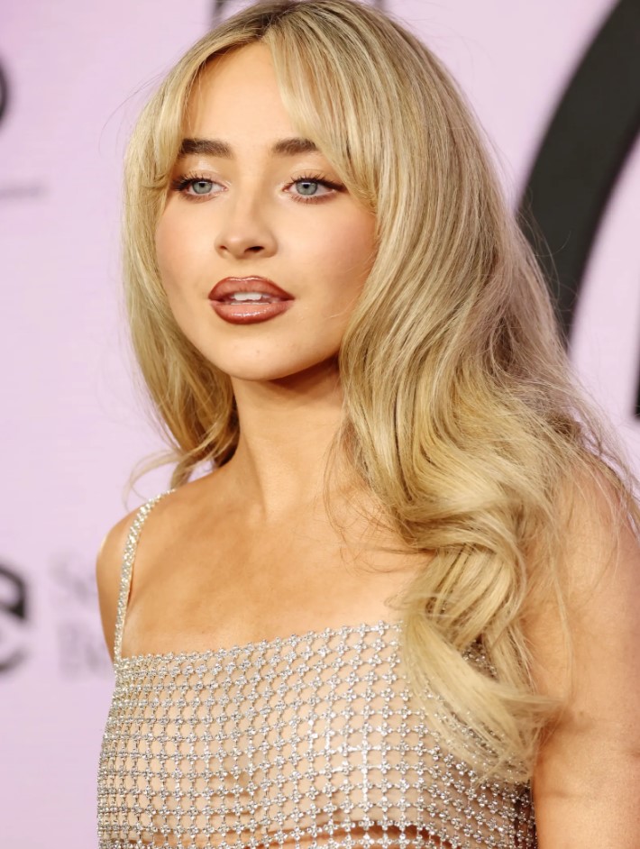 Sabrine Carpenter wearing long expensive blonde locks with side bangs and waves looks jaw-dropping