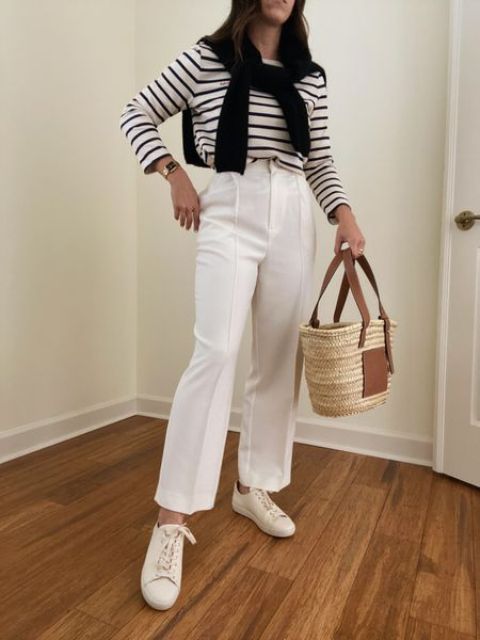 a Breton stripe top, white trousers, white sneakers, a black jumper over the shoulders and a straw bag for spring
