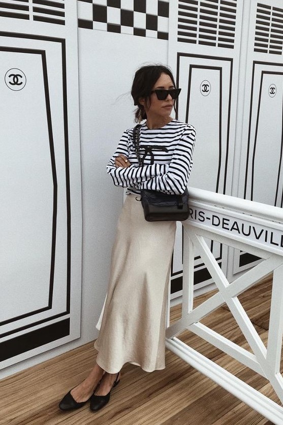 a Breton striped top, a champagne-colored midi slip skirt, black slingbacks and a black bag for a girlish look