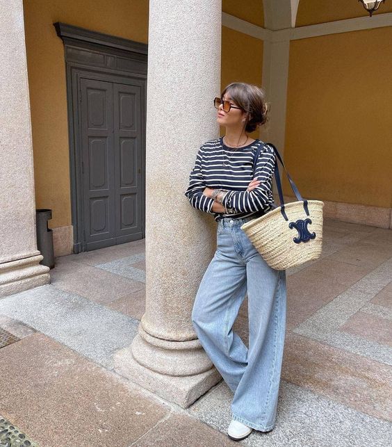 a navy and white Breton stripe top, blue wideleg jeans, white sneakers, a straw bag are a lovely combo for a weekend