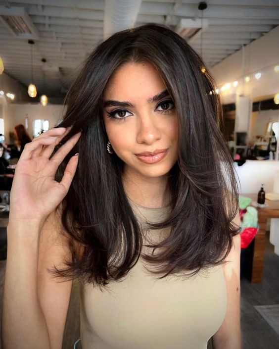 a beautiful and voluminous dark chestnut haircut with layers and side bangs is a very chic and bold idea