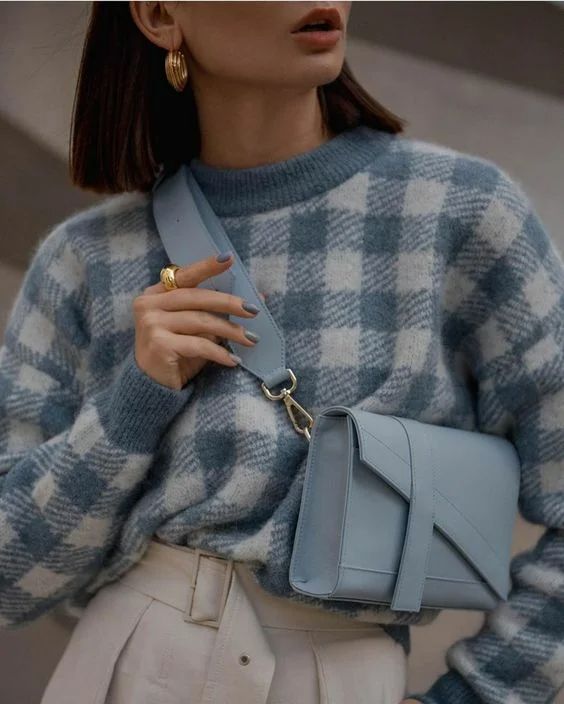 a blue and white plaid sweater, white leather pants with a belt and a dusty blue leather bag are a chic look