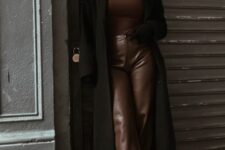 a brown turtleneck, brown leather trousers, black chunky boots, a black midi coat and a cap for a cozy winter look