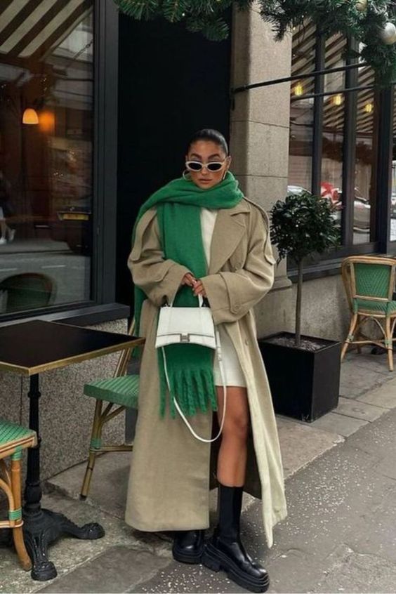 a creamy sweater dress, a neutral maxi trench, black boots, an oversized green scarf and a neutral bag