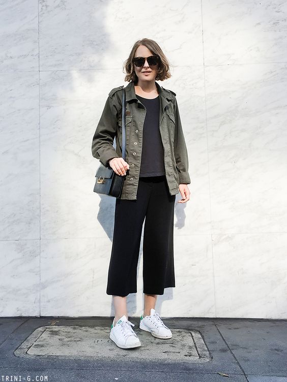 a grey t-shirt, black culottes, white sneakers, a green utility jacket, a black bag are a moody and cool look for spring