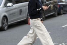 a navy sweater with buttons on the sleeves, white wide leg jeans, black slingbacks and a bold red bag