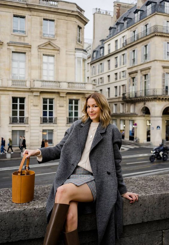a neutral jumper, a grey plaid mini, a grey coat, brown knee boots and an amber bucket bag are a lovely and chic combo