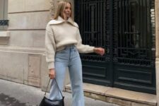 a neutral polod sweater, bleached blue jeans, two-tone boots and a small black bag are a lovely look